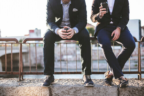 Two businessman sitting outside having coffee.