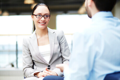 Young businesswoman with hair pulled back interviewing a businessman.