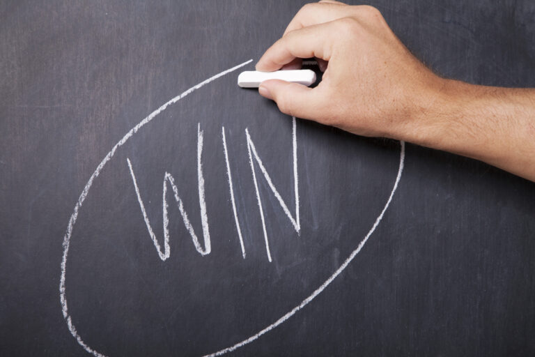 A photo of the word "win" written on a chalk board. The word is circled.