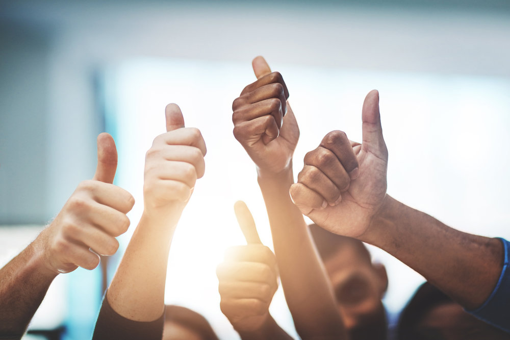 People standing in a circle with their thumbs up.