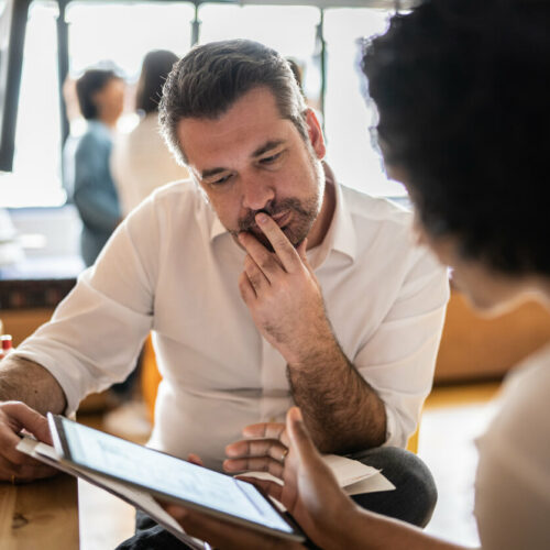 Salesperson deciding what he should do sitting at table with woman.