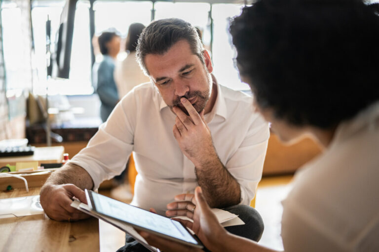 Salesperson deciding what he should do sitting at table with woman.