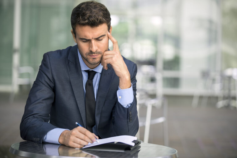ocused businessman thinking and writing outside office
