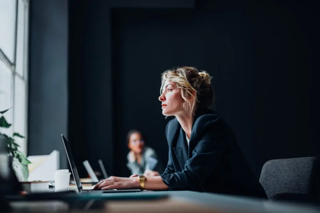 woman at desk with black wall background